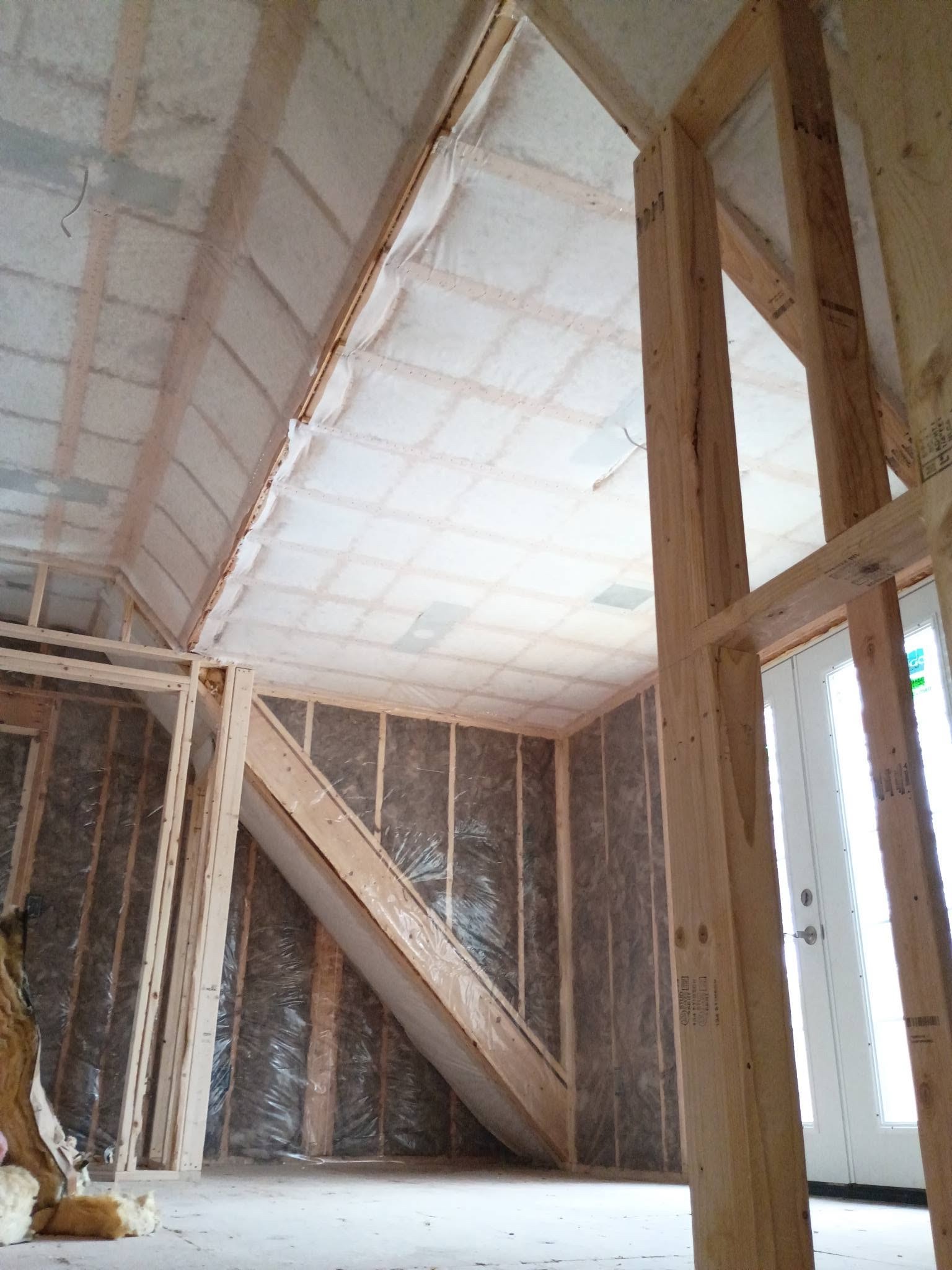 Fiberglass batt insulation and vapor barrier around stairwell framing in an Amesbury Massachusetts addition