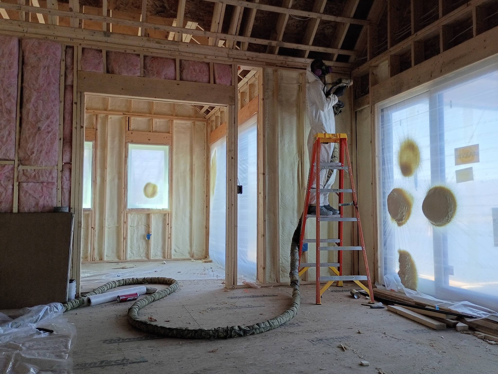Installer applying spray foam insulation inside a New Hampshire lakehouse