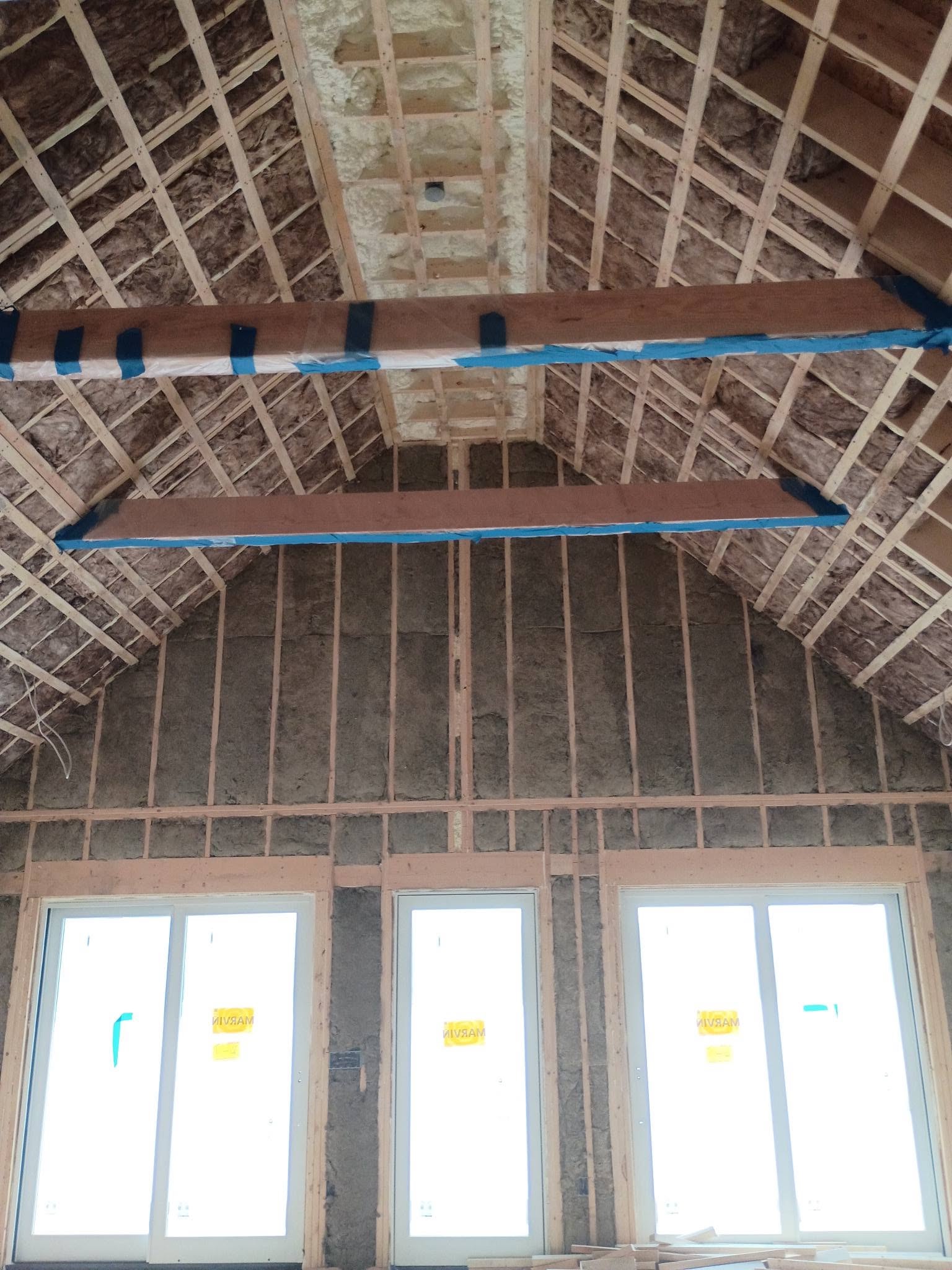 Vaulted lakehouse room with fiberglass batt insulation in walls and roof framing in New Hampshire