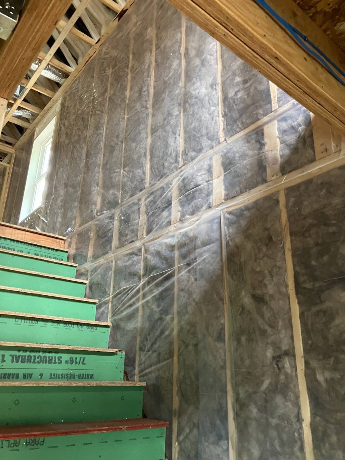 Fiberglass batt insulation with vapor barrier in a New Hampshire new home stairwell